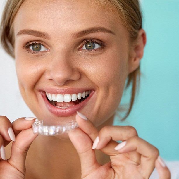 Patient smiling while holding teeth whitening tray
