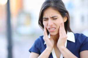Young woman holding face in pain. 