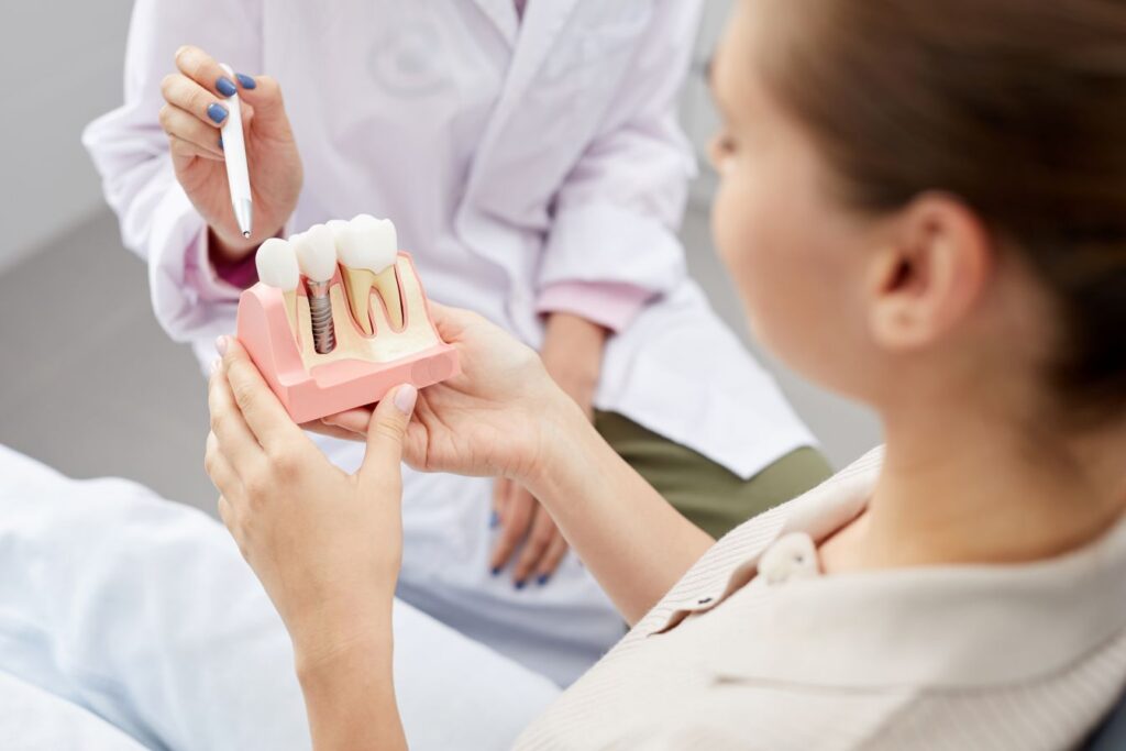 A dentist showing a patient a model of a dental implant in the jaw