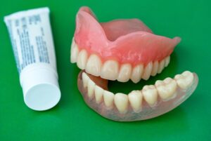 Dentures pictured next to denture adhesive.
